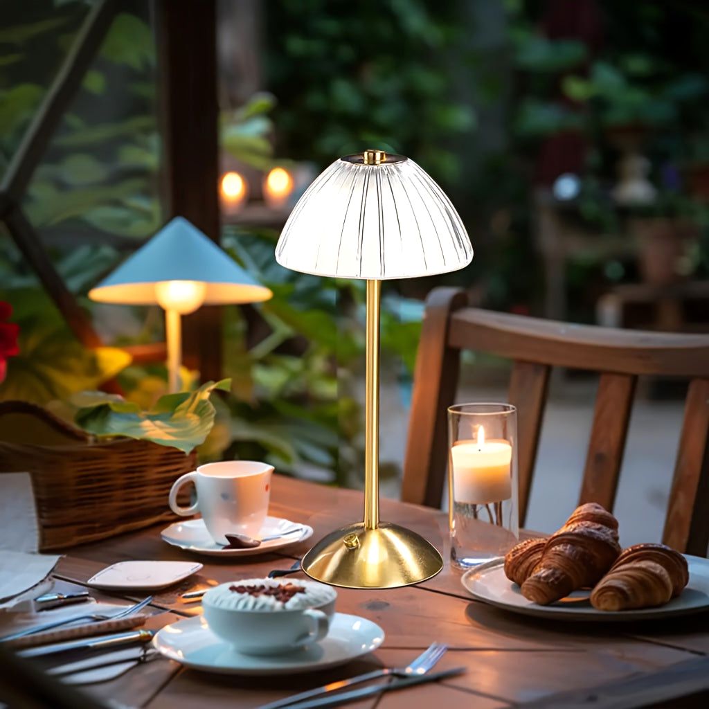 Luxe Glow USB rechargeable table lamp with an elegant gold finish, illuminating a dining table set croissants, coffee, a candle in an outdoor patio.