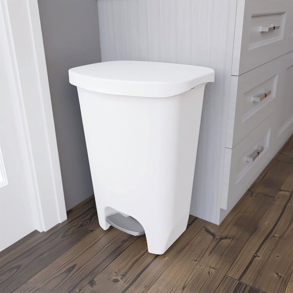 A white Serenity kitchen trash can with a step pedal, placed beside white kitchen cabinets on a dark wooden floor, showcasing its sleek design.