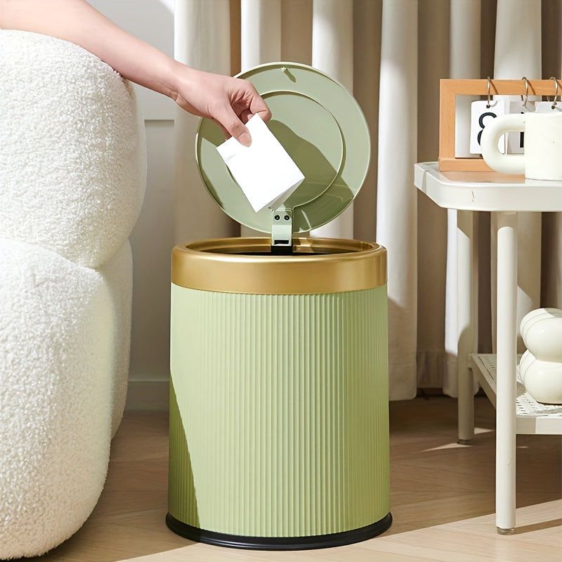 Green Elegance Oval Waste Solution trash can with a press-top lid, shown in a living room setting with a hand dropping paper into it. Features a premium design and dual inner bucket.