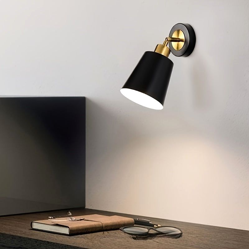 Black Luna Glow adjustable wall sconce light with brushed metal finish, illuminating a wooden desk with glasses and a notebook, creating a modern workspace ambiance.
