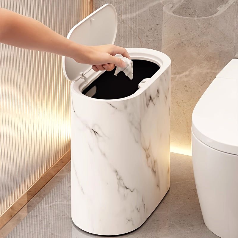 A hand dropping a tissue into the open lid of a Cream White Luxe Marble Canister, demonstrating its functional design as a modern trash can with a secure lid.