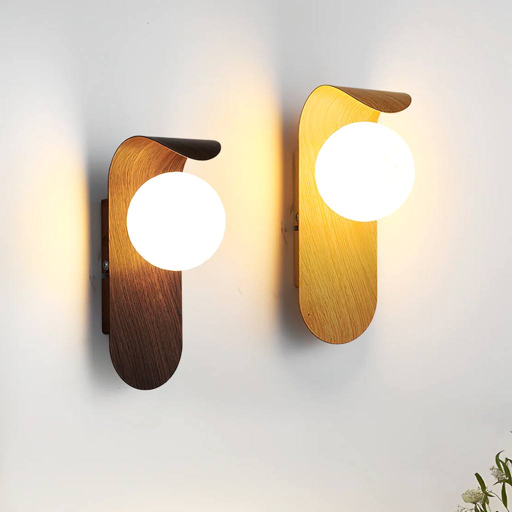 Two Nordic Glow LED wall sconces, one in light wood and one in dark walnut wood, both illuminated and mounted side by side on a white wall, showcasing both variants.