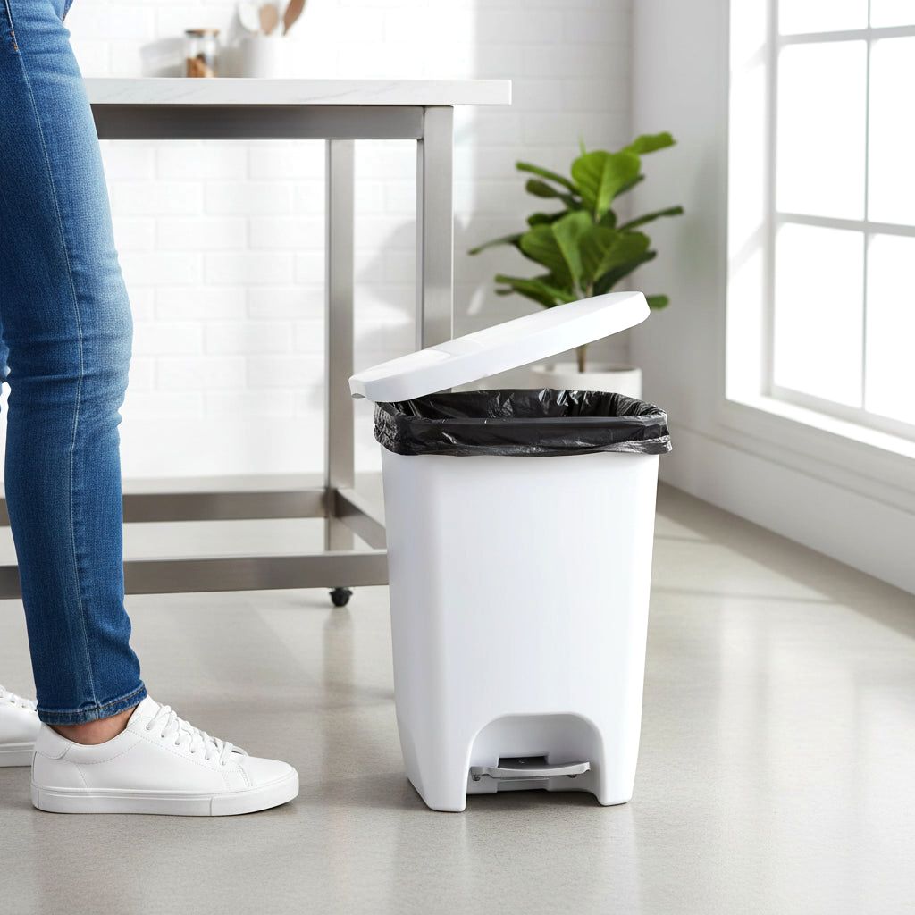 A white Serenity kitchen trash can with its lid open, showing a black trash bag, placed in a bright kitchen with a person standing nearby.